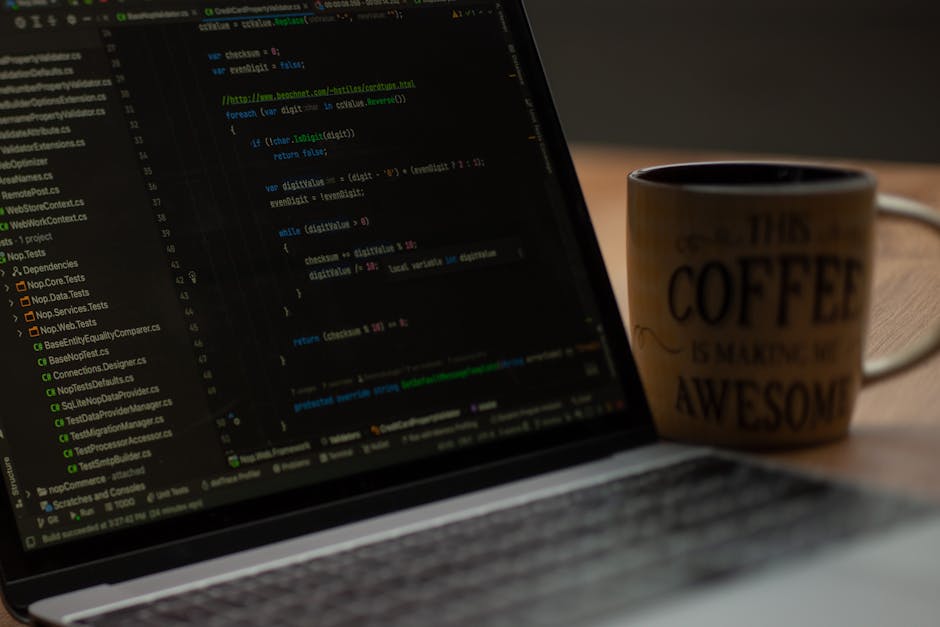A close-up view of a laptop screen displaying lines of code in a dark-themed code editor, situated on a wooden desk. To the right of the laptop, there is a ceramic mug with a beige exterior featuring 